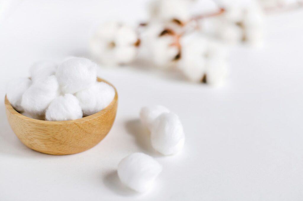 Cotton balls for cleansing with natural cotton flowers on white background with copy space